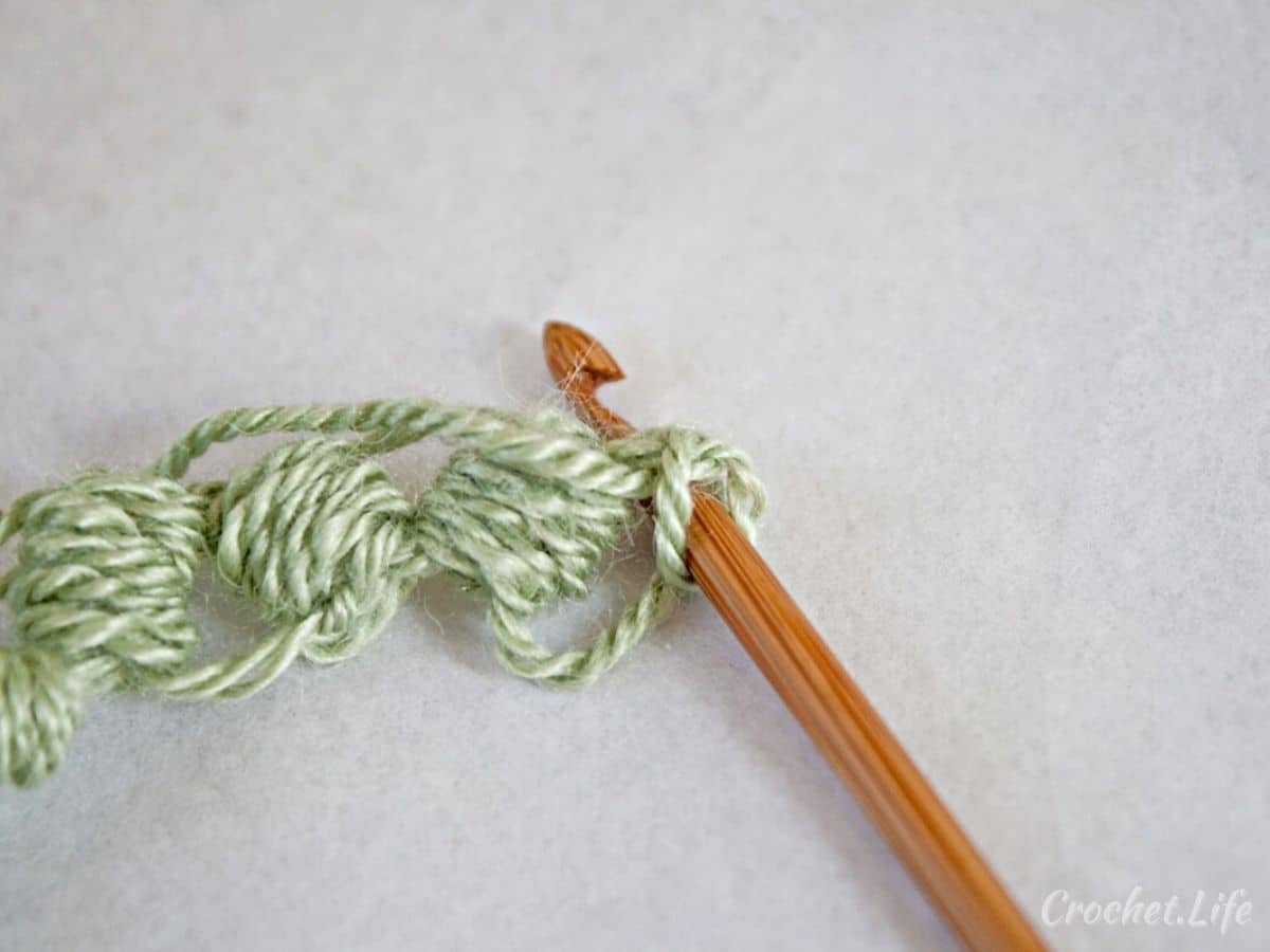 Green yarn on wooden crochet hook