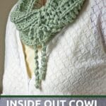 Woman in white sweater with green cowl with fringe