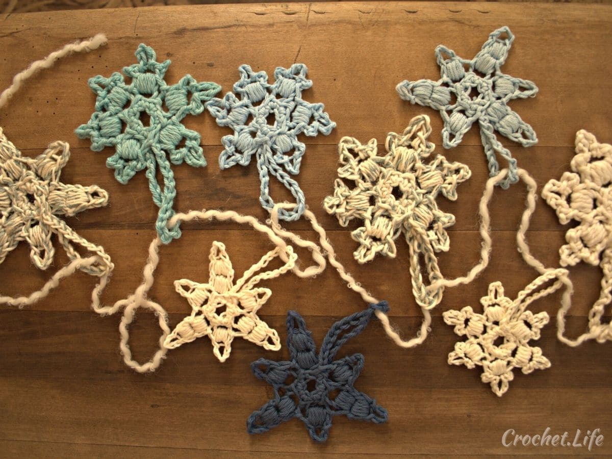 Several crochet snowflakes laying on wood table