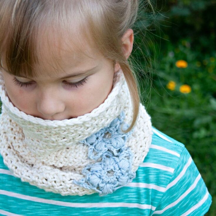 Girl in teal striped shirt wearing crocheted white and blue cowl
