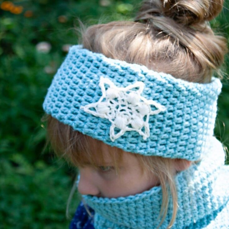Blonde girl in blue shirt wearing light blue cowl and matching headband with white snowflakes