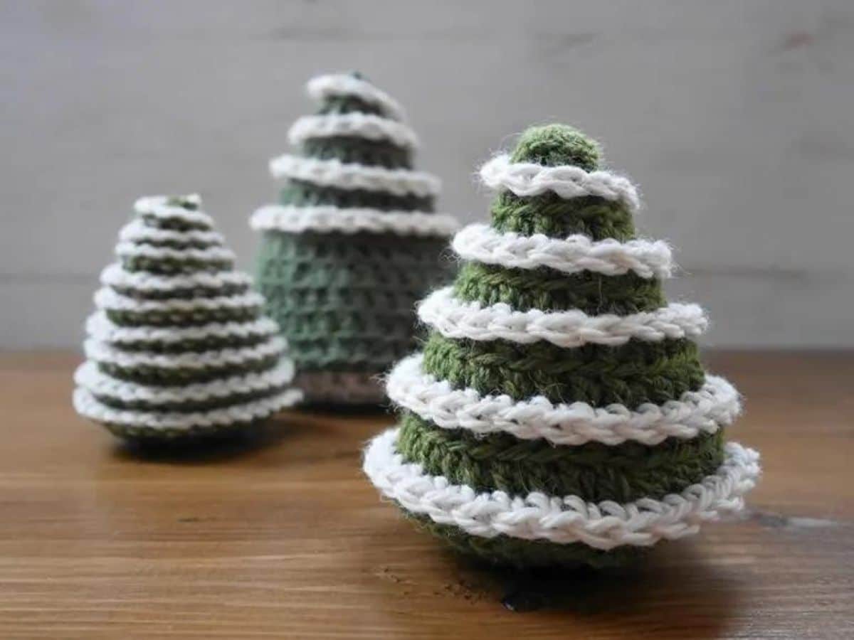 Small 3-D crochet Christmas tree with white ruffles next to two smaller Christmas trees with the same design. 