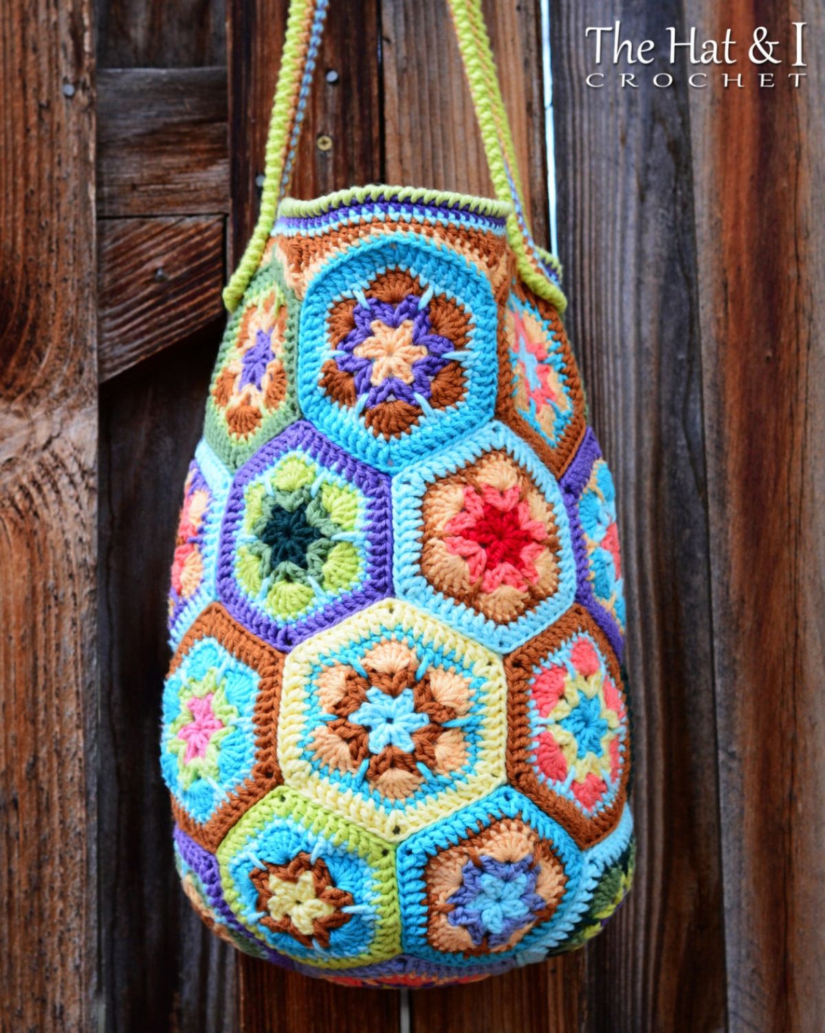 Brightly colored crochet bag with hexagons of African flowers stitched together in yellow, blue, purple, green and orange hanging from green straps.