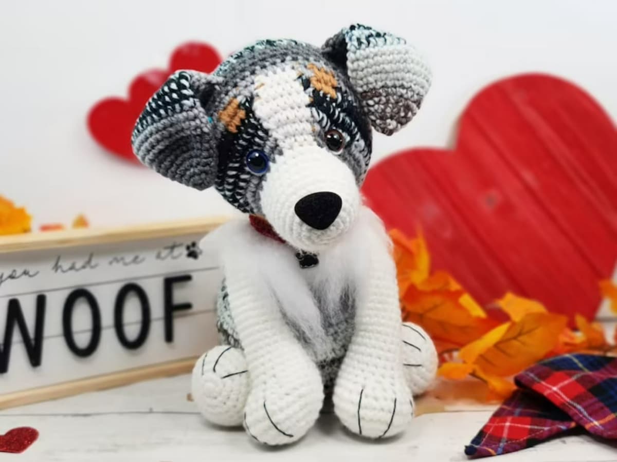 Crochet stuffed Australian Shepherd with a white face and body and grey and black striped ears and eyes.