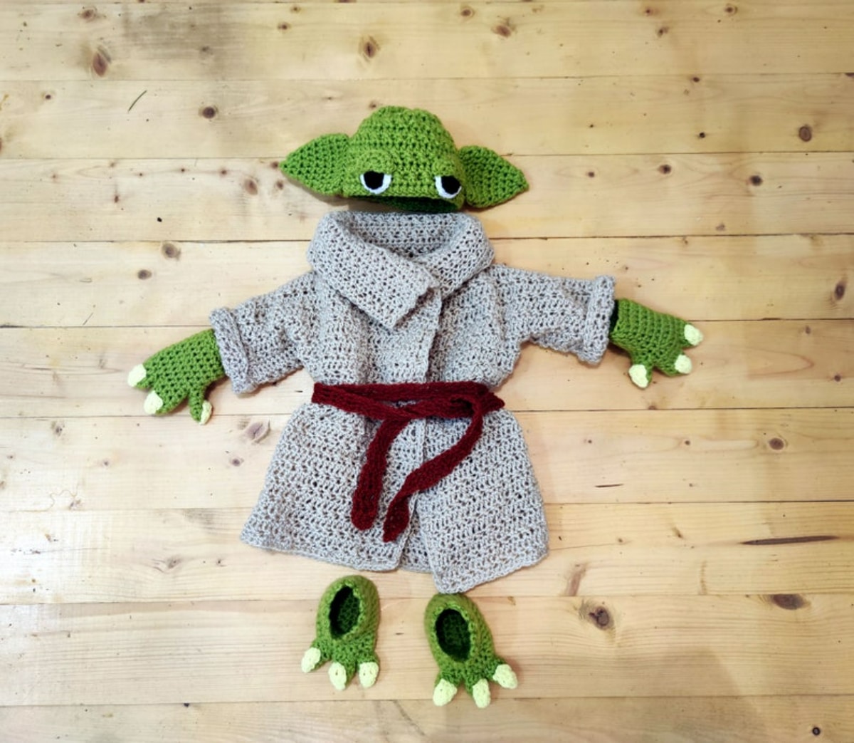 Green crochet baby Yoda beanie hat with matching green gloves, shoes and a gray robe with a brown belt around the middle.