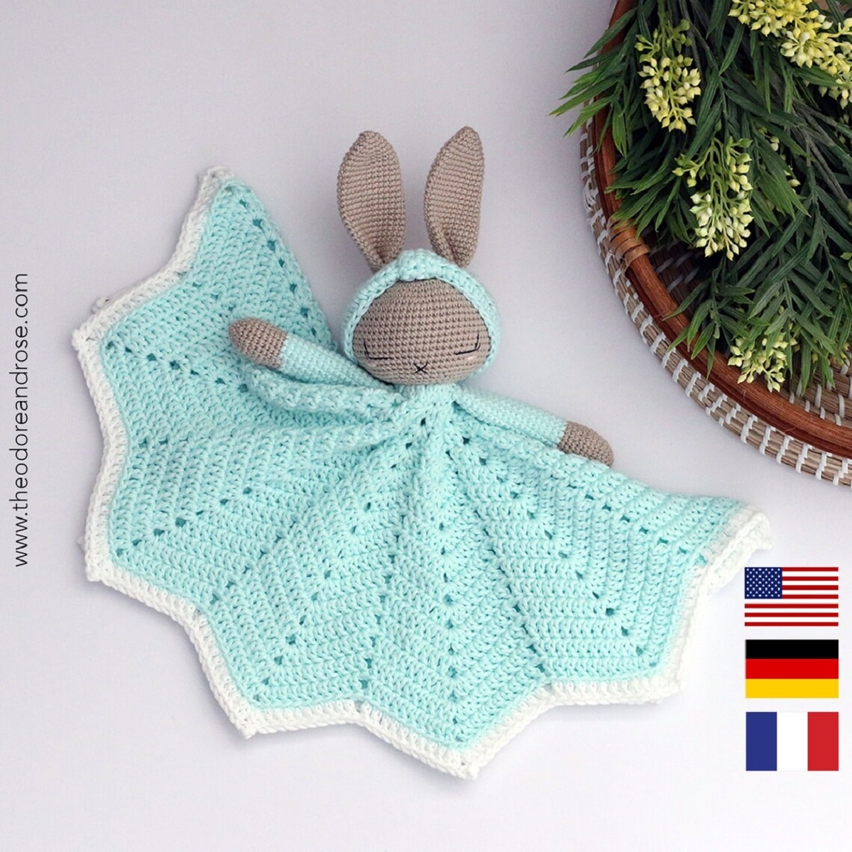 Blue crochet blanket with a zig zag hem and brown bunny head and blue arms attached to the top on a white background.