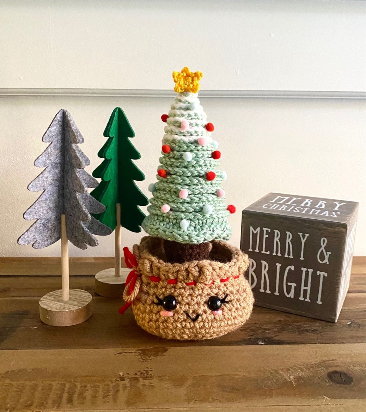 A small green and white Christmas tree with red and white bobbles on and a star on top sitting in a burlap style sack.