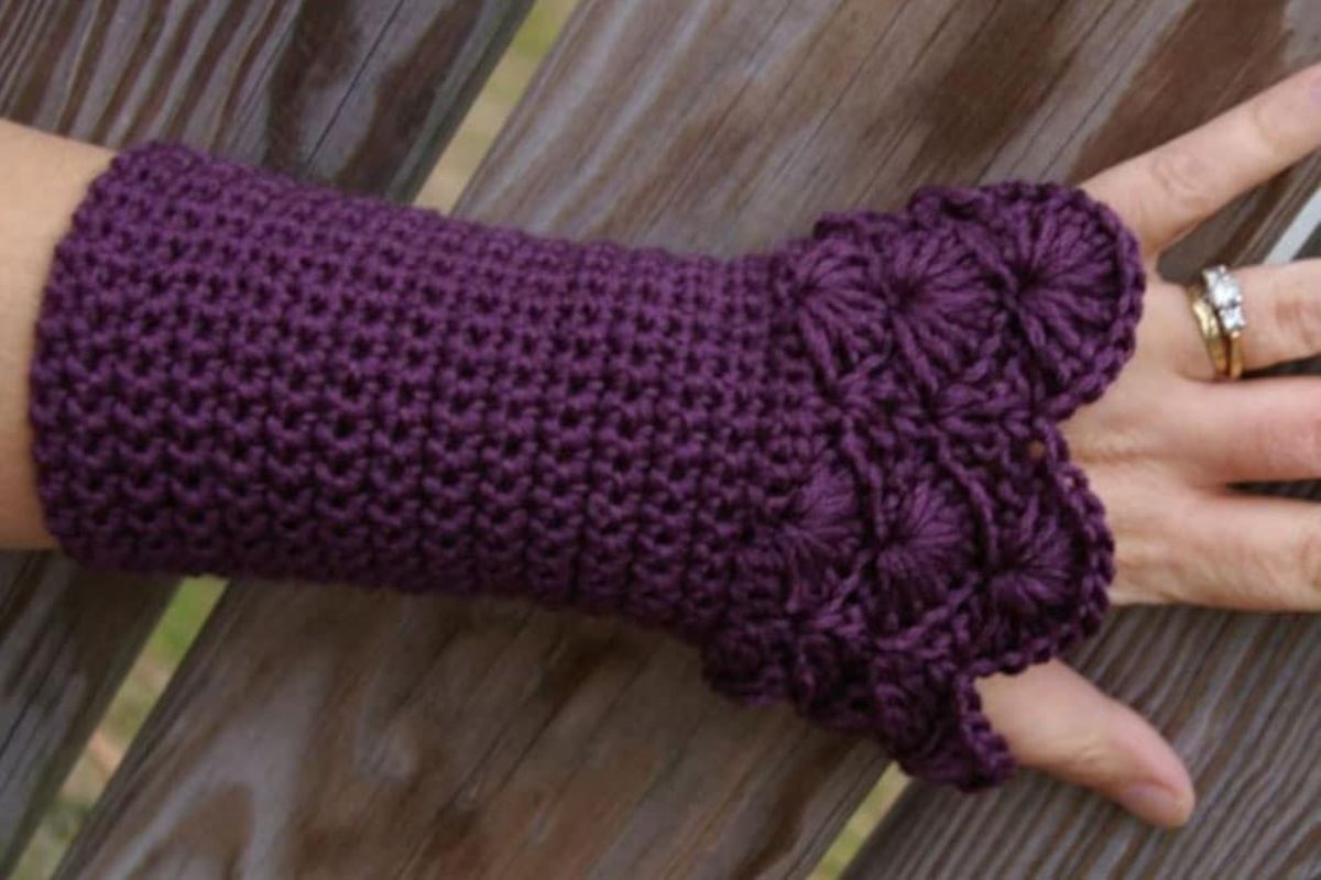 Dark purple fingerless gloves that cover the entire wrist with an intricate fan pattern on the hand portion of the gloves.