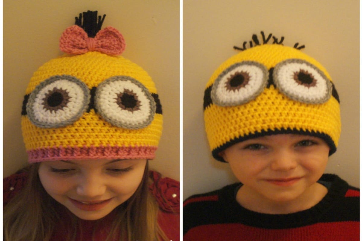 A young girl and boy wearing minion style beanie hats, one with a pink boy at the top, the other black spikes for hair.