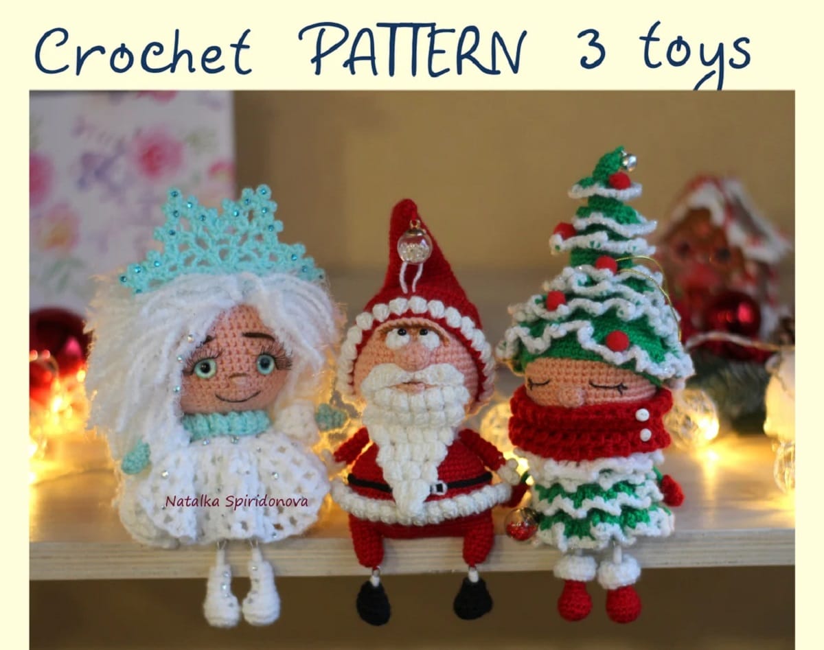 A crochet doll with white hair, dress, and a blue snowflake on her head sitting next to a Santa and a doll dressed as a Christmas tree.