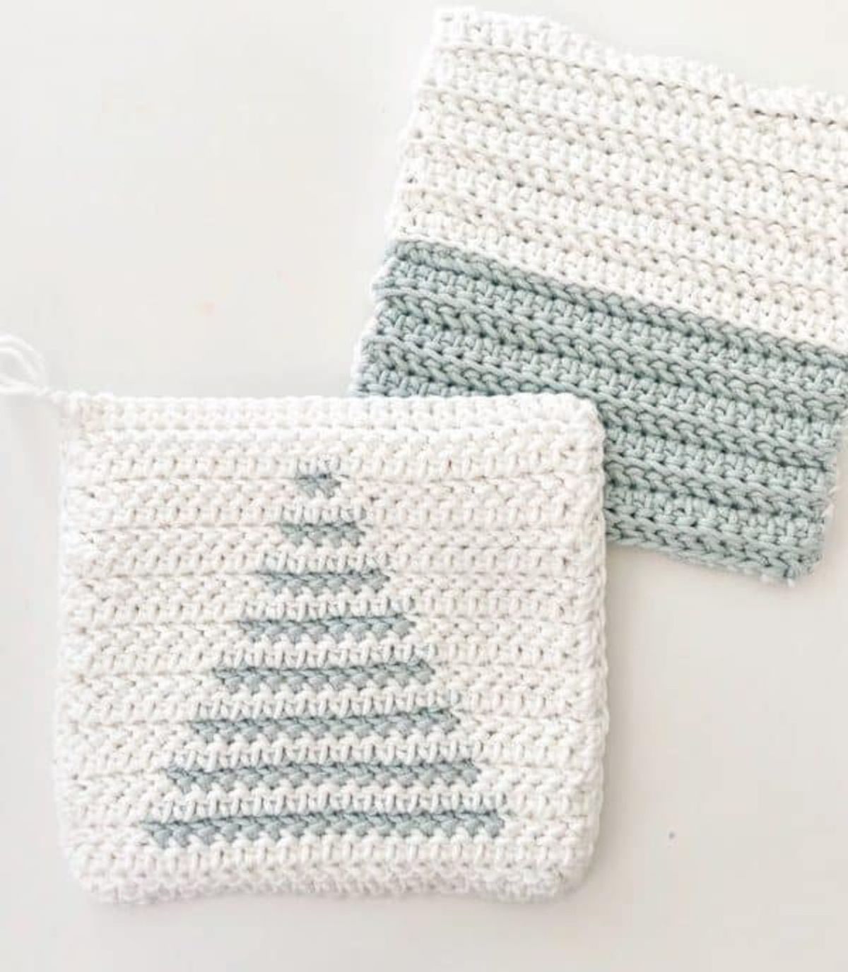 A white crochet potholder with a light green Christmas tree in the center next to a striped white and green potholder.