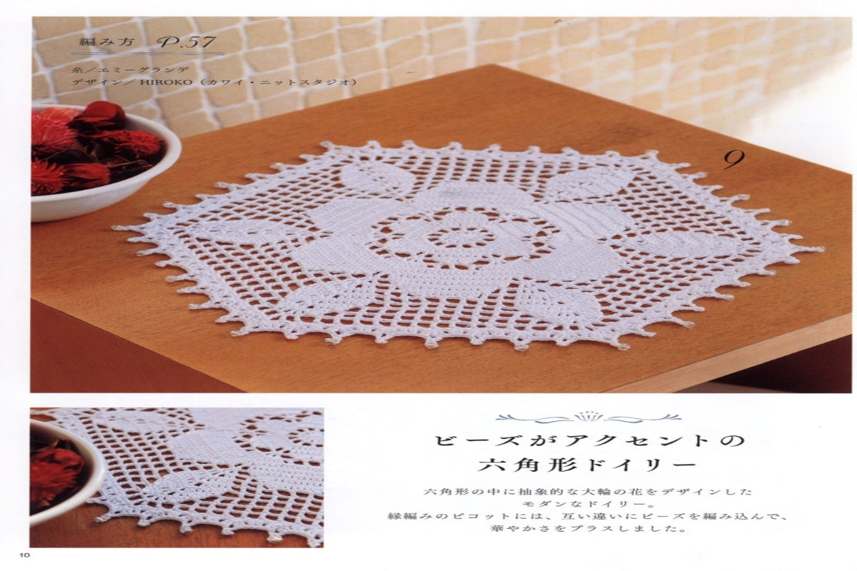A white lacy hexagon crochet doily with a large flower in the center and its leaves hitting each point of the hexagon.