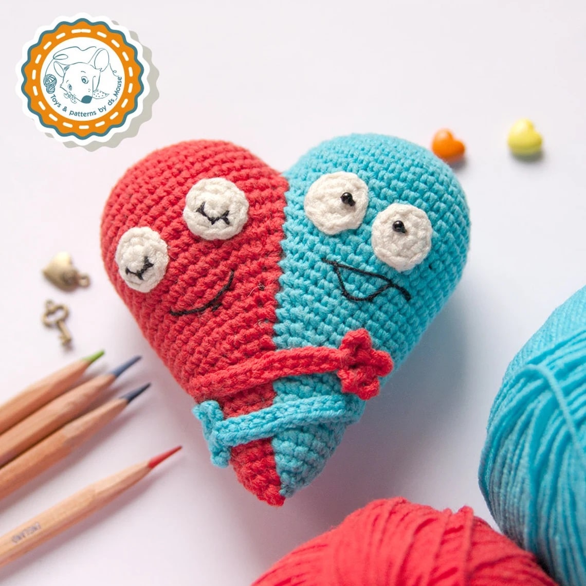  Half a red crochet heart and blue heart stitched together with hands wrapped around hugging and black eyes and mouths stitched on.