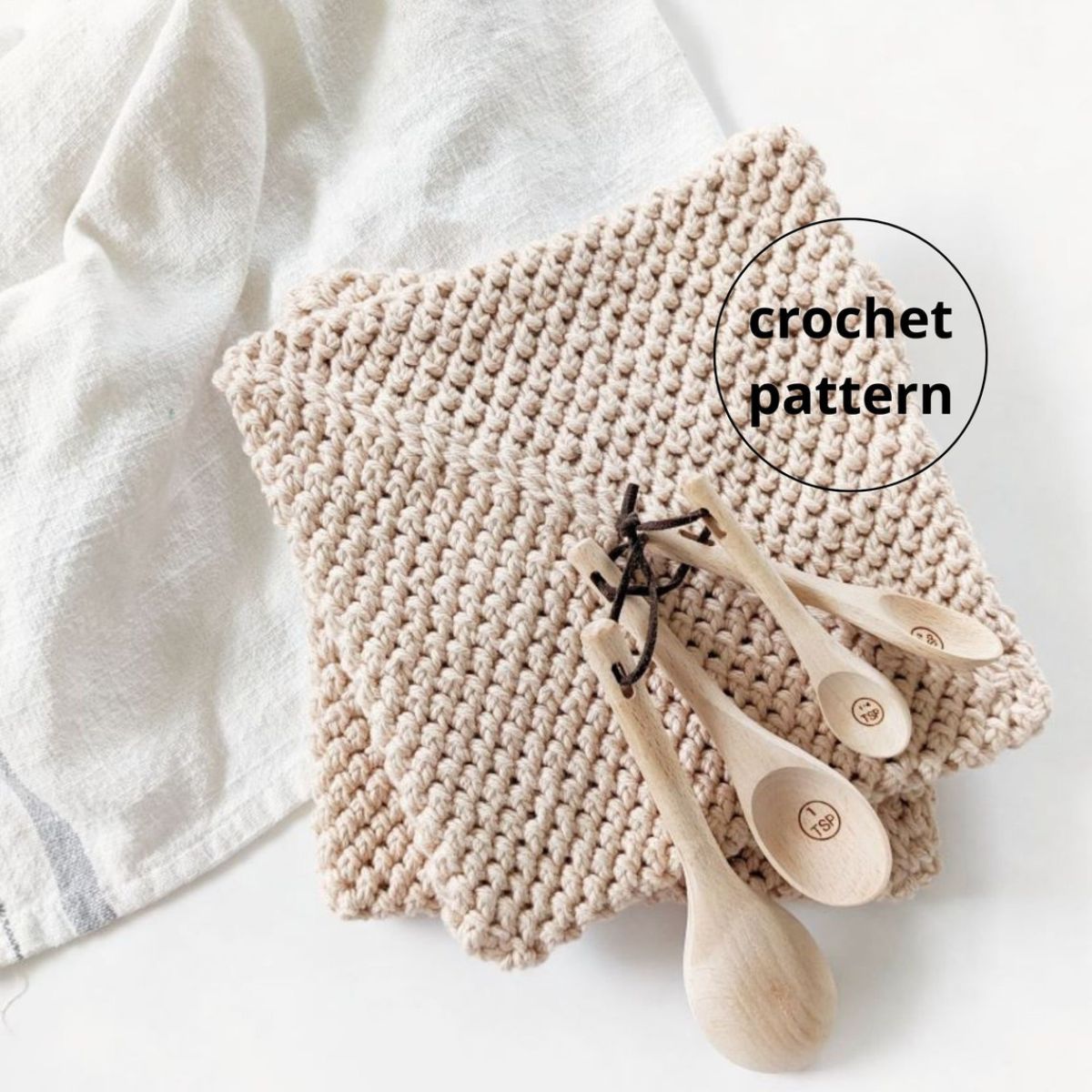 Two beige crochet potholders stacked on top of each other with a small wooden spoon set next to them.