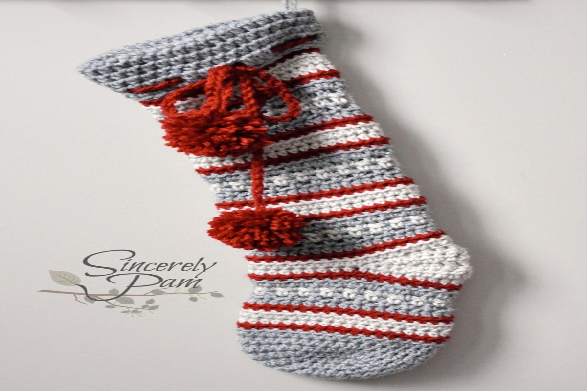 Gray, white, and red stocking with small white spotted design. Large red bobble and bow sits under the gray banding. 