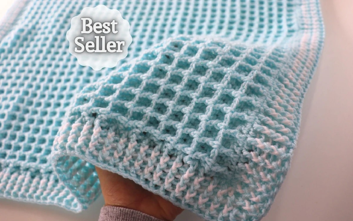 Aqua blue waffle style crochet baby blanket with a cream and blue vertical trim all round on a white background.