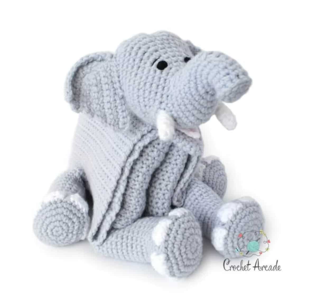 Large gray crochet blanket with a stuffed elephant head and legs attached to it. The elephant has small white tusks and white feet.
