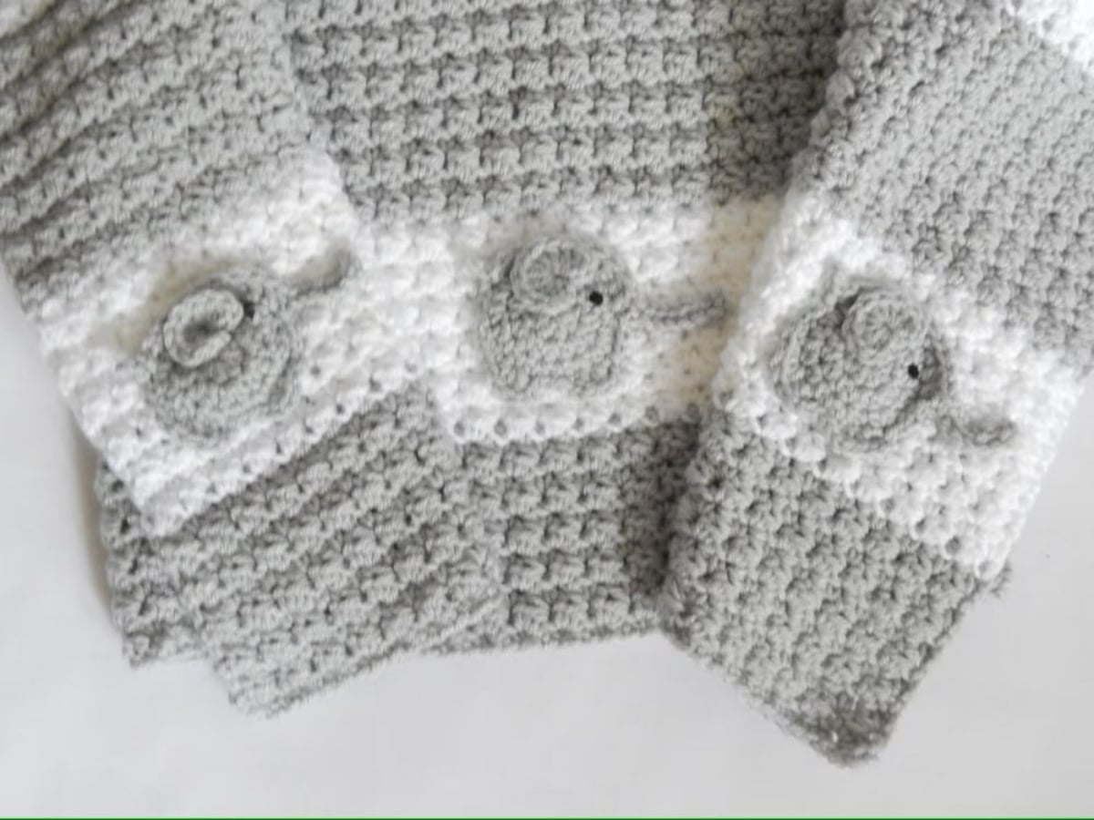 Gray and white striped crochet blanket with small gray elephants stitched into the white rows on a white background. 