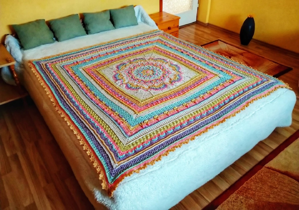 A large square crochet throw with different colored squares getting smaller and a flower mandala in the center.