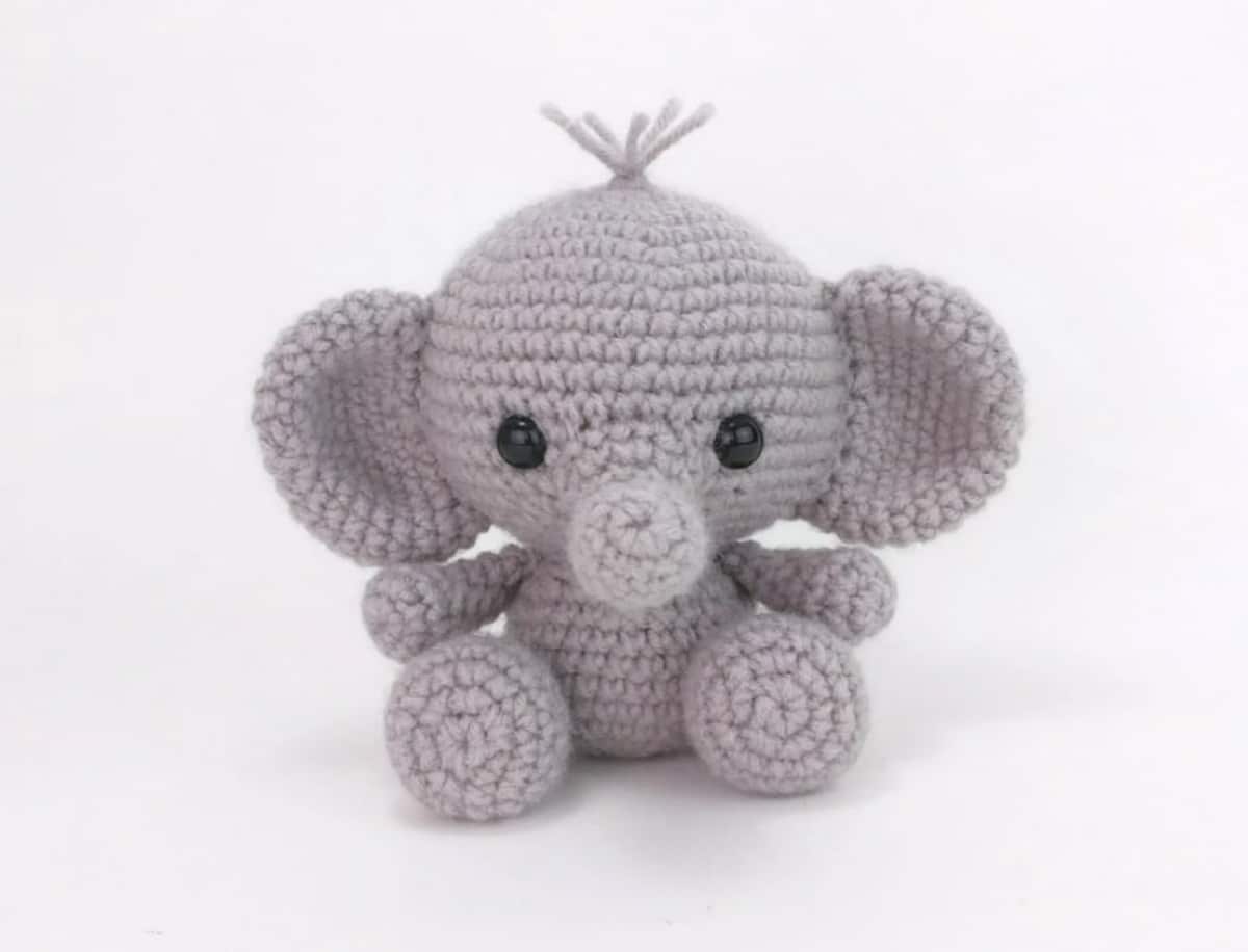 Miniature gray crochet elephant with a small trunk, black eyes, and little gray spikes of hair at the top of his head.