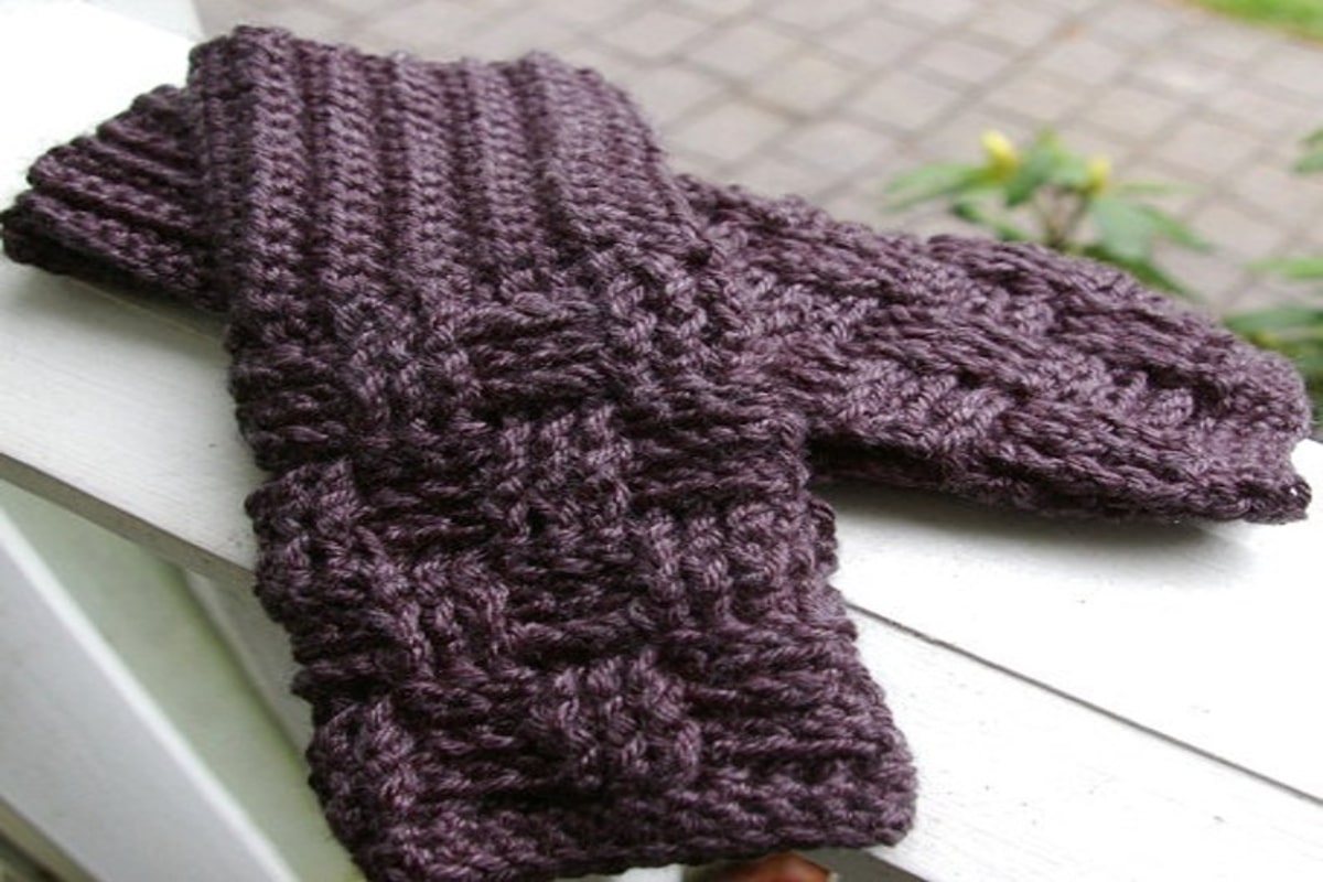  A pair of purple basketweave fingerless gloves layered on top of each other on a white background.