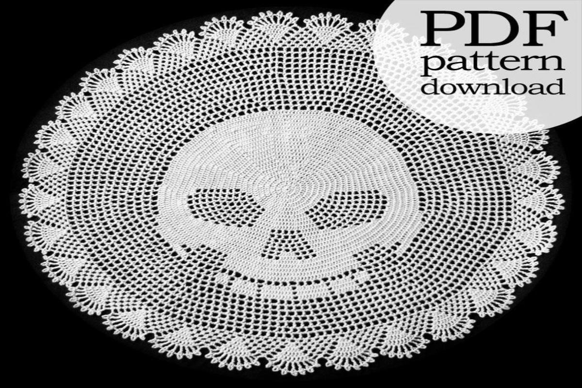 A large white round crochet doily with a skull in the middle and a fan pattern on the outside.