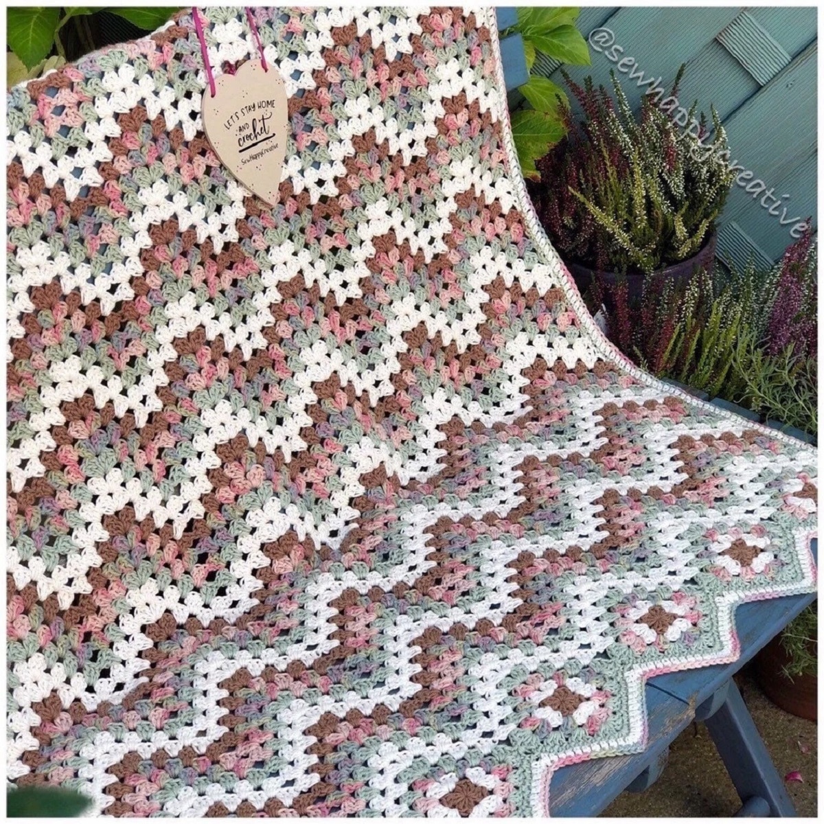 Green, pink, brown, and white chevron style crochet blanket with small granny squares at the bottom and a zig-zag hem.