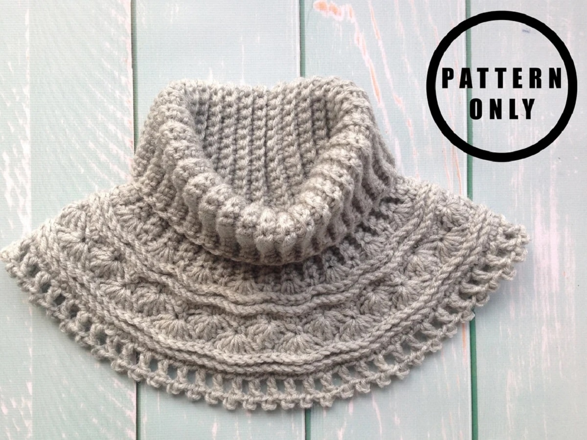 Gray high neck crochet cowl with a mixture of loose and tight stitches and a small line of bobbles at the bottom of the cowl.