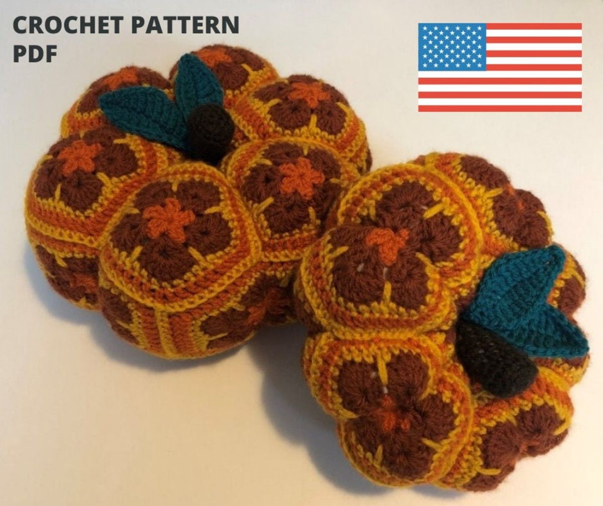 Two small crochet pumpkins made of crochet hexagons of dark brown and orange flowers with dark green leaves at the top of the pumpkins.