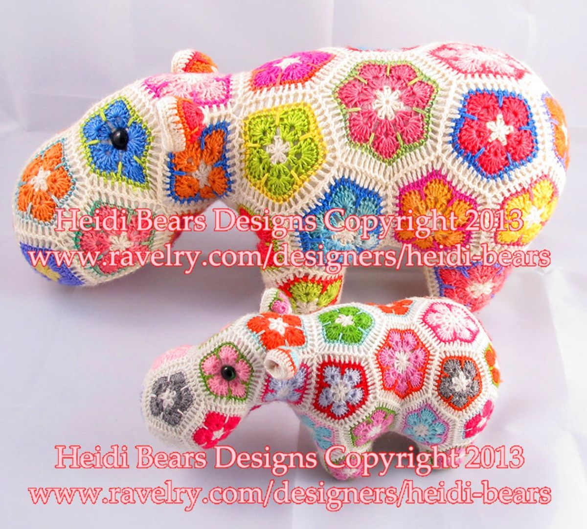 A large cream hippopotamus with yellow, pink, blue, and green crochet African flowers all over it and a smaller one in front in the same design.