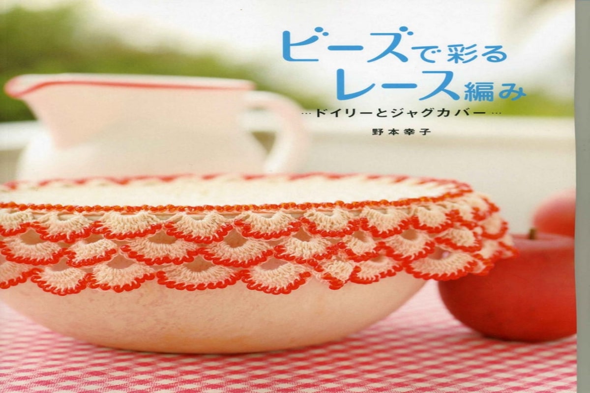 White bowl with a red and white ruffle crochet doily sitting on top with a white and red milk jug in the background.