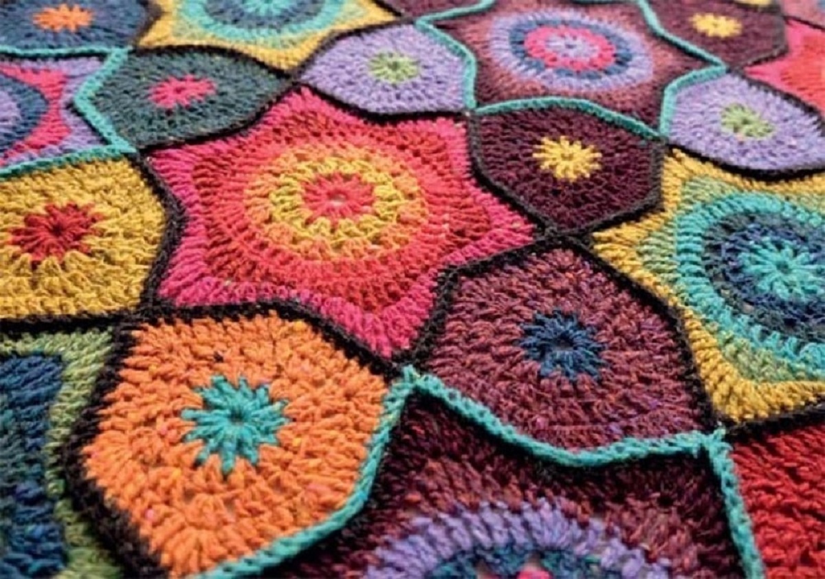Large crochet blanket with bright colored stars stitched together and a black outline around each star.