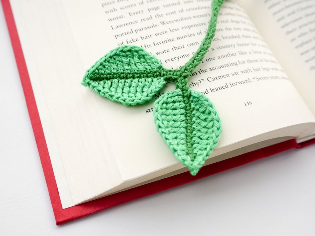 A light green crochet bookmark with two leaves at the top and a dark green line through both leaves.