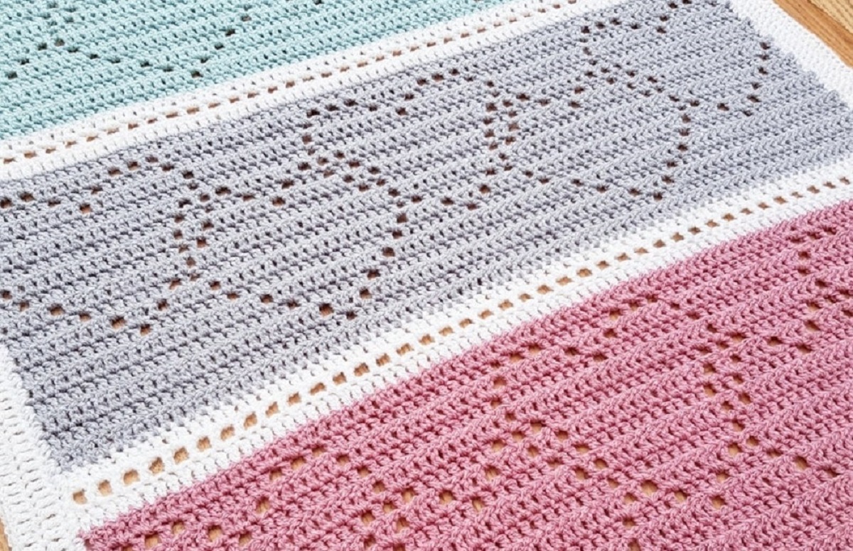 Pink, cream, purple, and mint green striped crochet blanket with linked hearts stitched into each stripe.