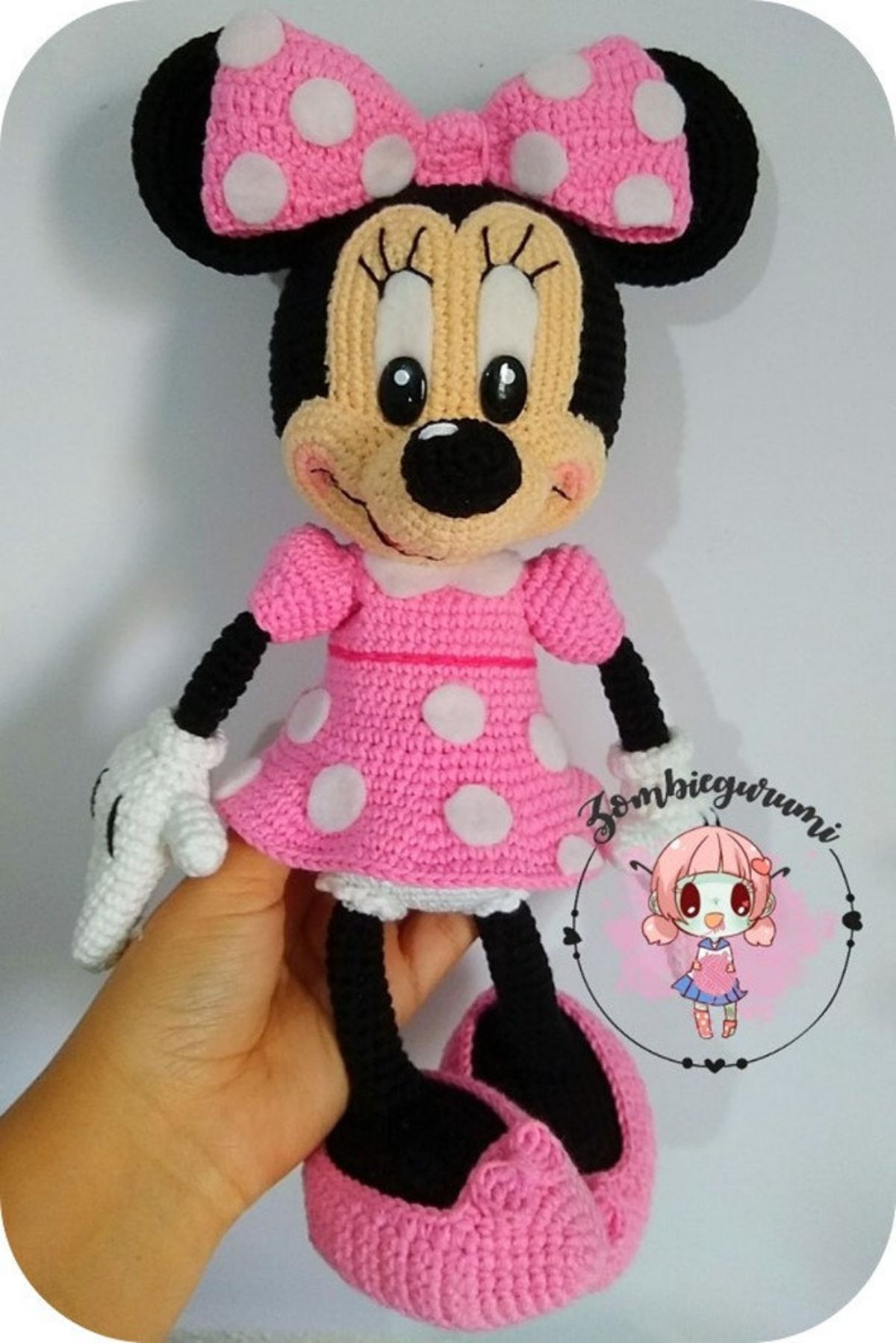 Large crochet Minnie mouse toy wearing a pink and white spotty dress, matching bow, and pink shoes.