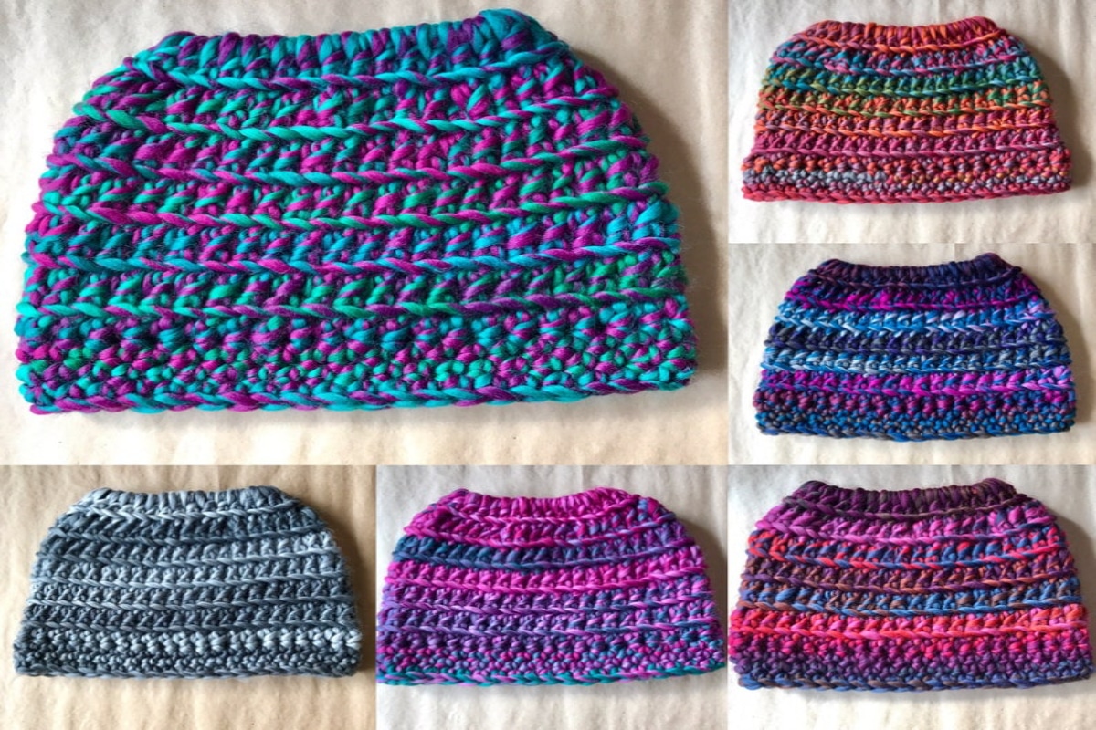 Six multicolored crochet hats with large holes at the top for a bun to fit through on a light wooden background.
