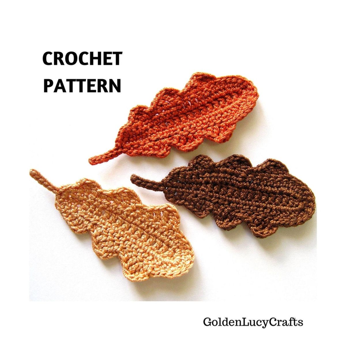 Three crochet oak leaves in yellow, orange, and brown lying next to each other with small stems on a white background.