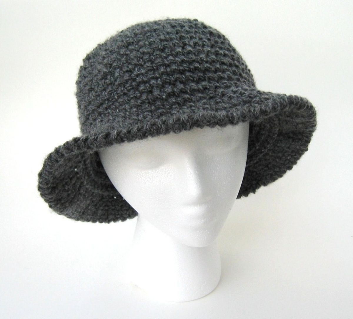 Mannequin wearing a green crochet skein hat with a large band around all sides of the hat.