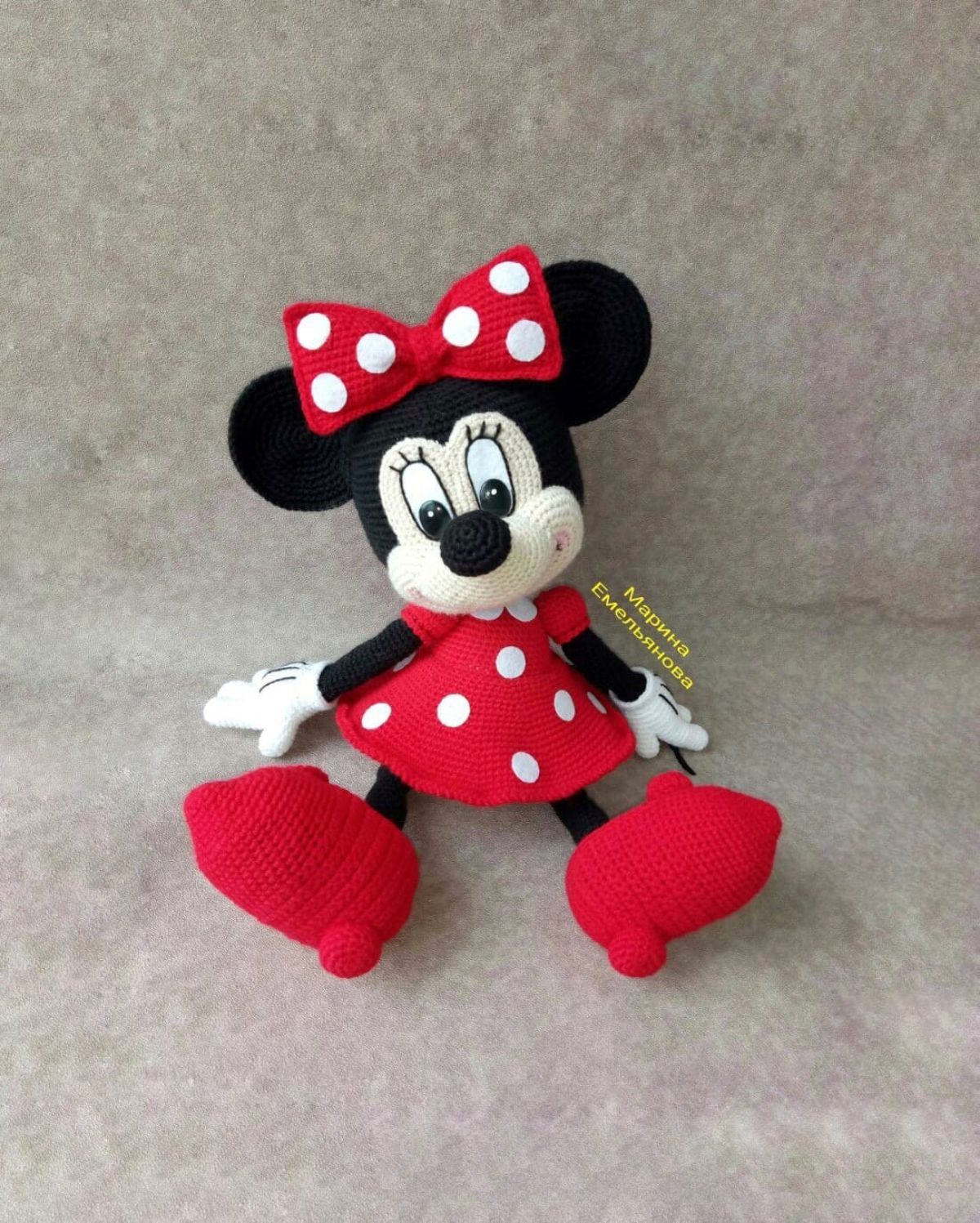 Small crochet Minnie Mouse toy with a red and white spotty dress, matching bow, and oversized red shoes.