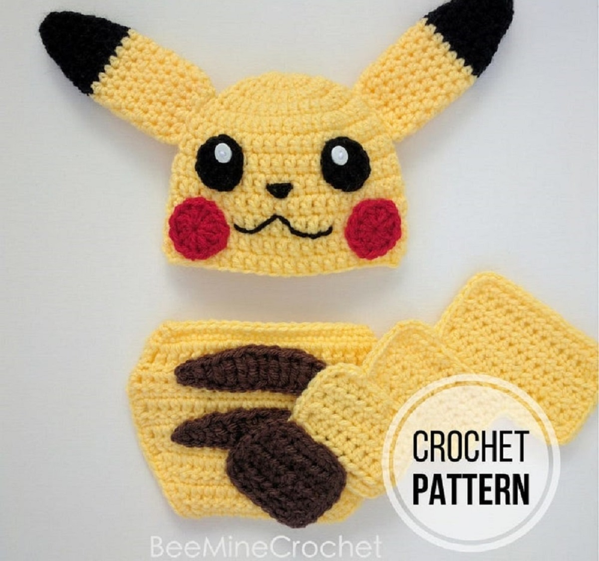 Crochet Pikachu beanie hat with large pointy ears either side, a yellow and brown striped diaper, and yellow scarf.