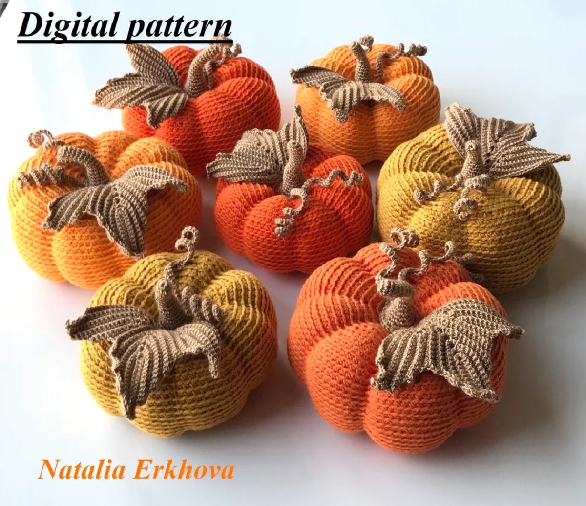 A pile of light and dark orange crochet pumpkins with brown stems in the center and a large brown leaf on each pumpkin.