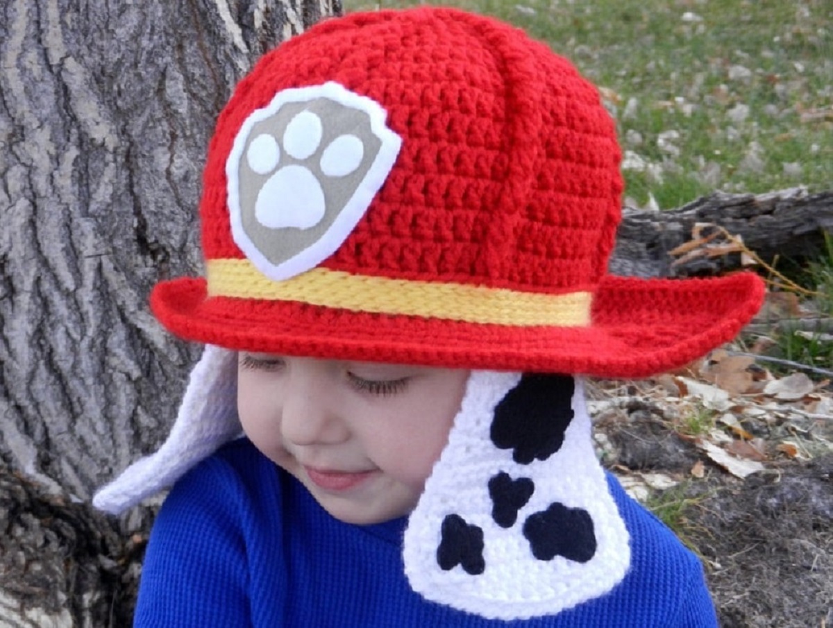 Small boy facing sideways wearing a Paw Patrol Marshall crochet hat with white and black ears dangling either side.