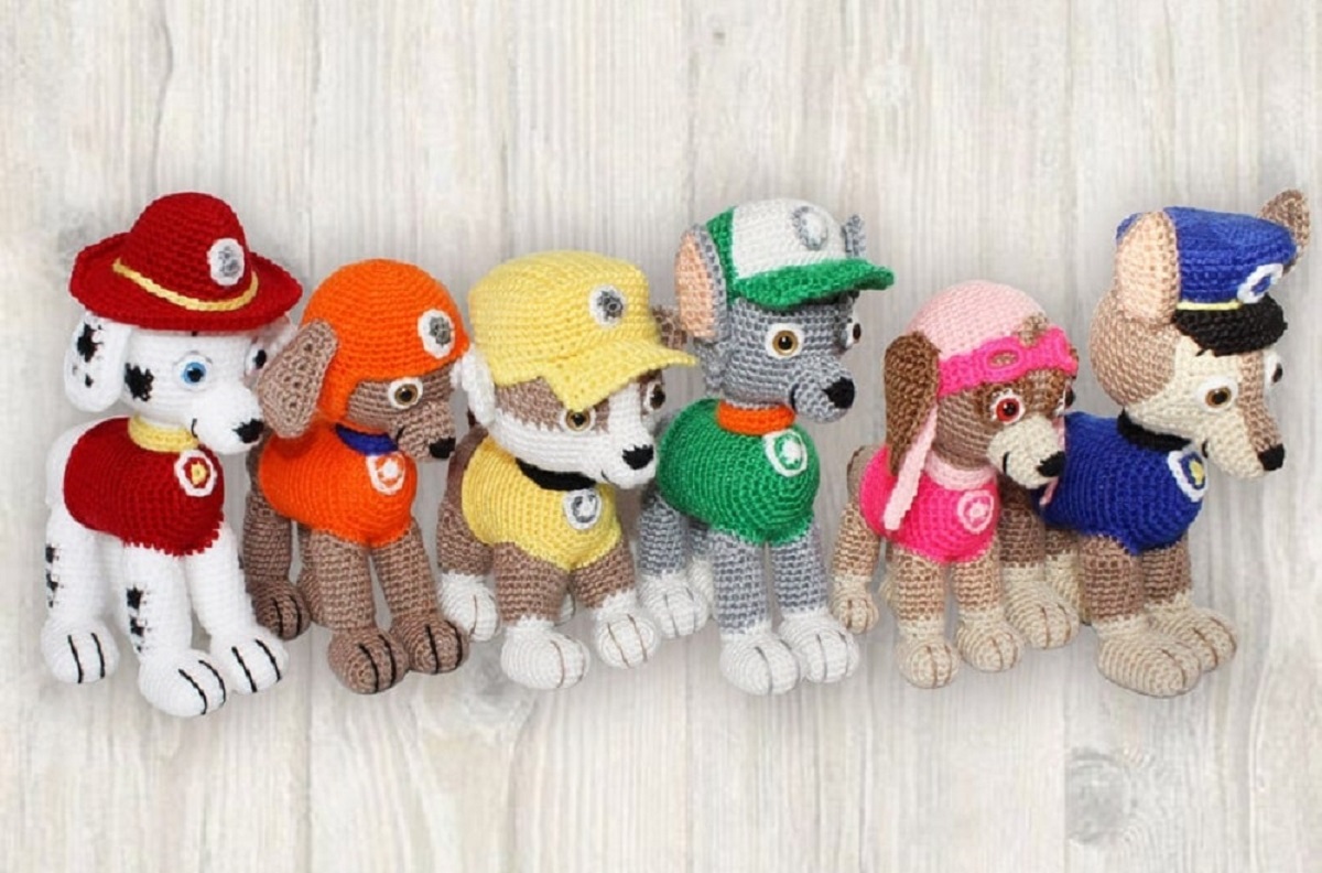 Small stuffed crochet toys of the six main Paw Patrol characters standing in a line on light wooden flooring.