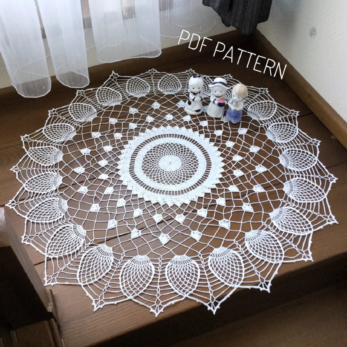 Large round cream crochet doily with five circles in the center, small white pineapples in circles spreading out to large pineapples in petals along the edges.