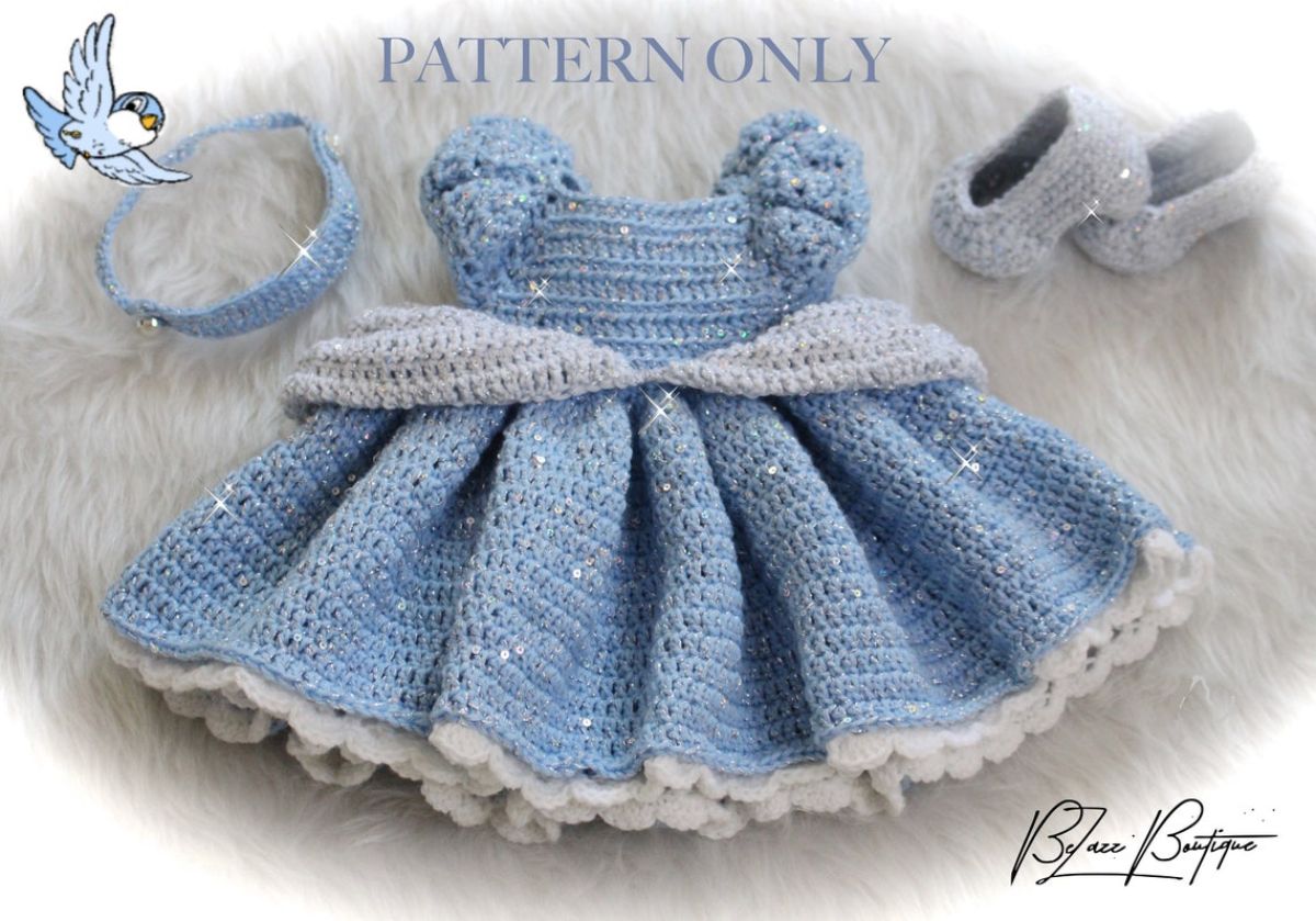 Blue crochet Cinderella style baby dress with a blue headband and gray slip on shoes.