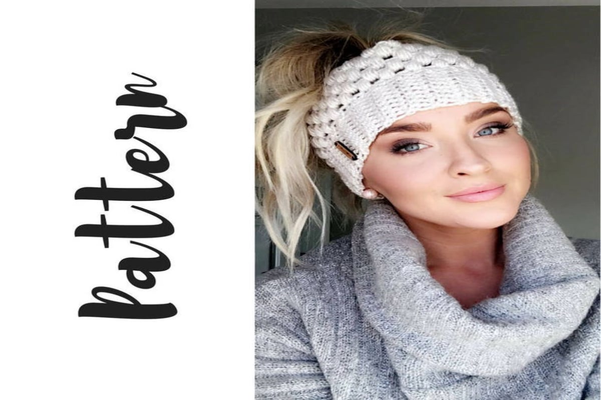 Blond woman in a gray jumper wearing a cream chunky crochet hat with a ponytail pulled through the top.