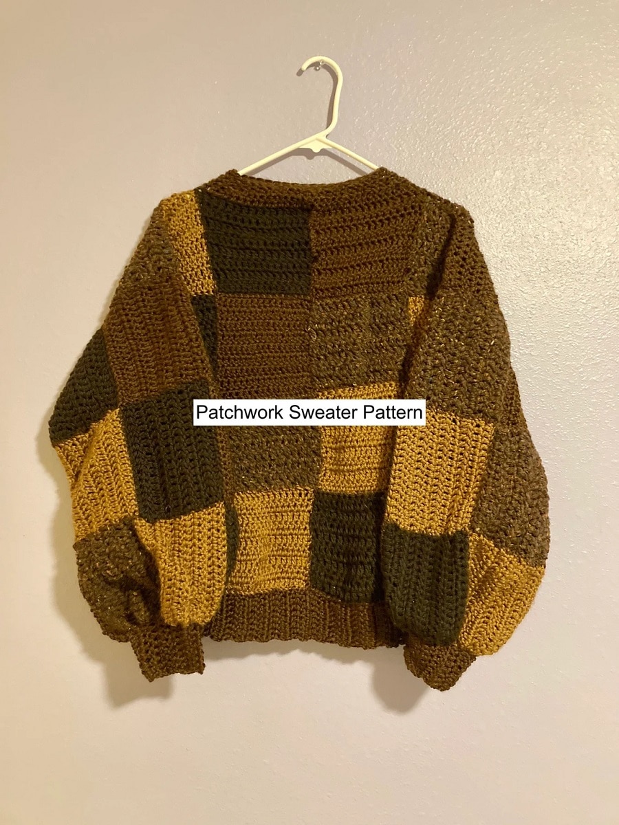 Light brown and dark brown patchwork crochet sweater with long cuffed sleeves on a white hanger.