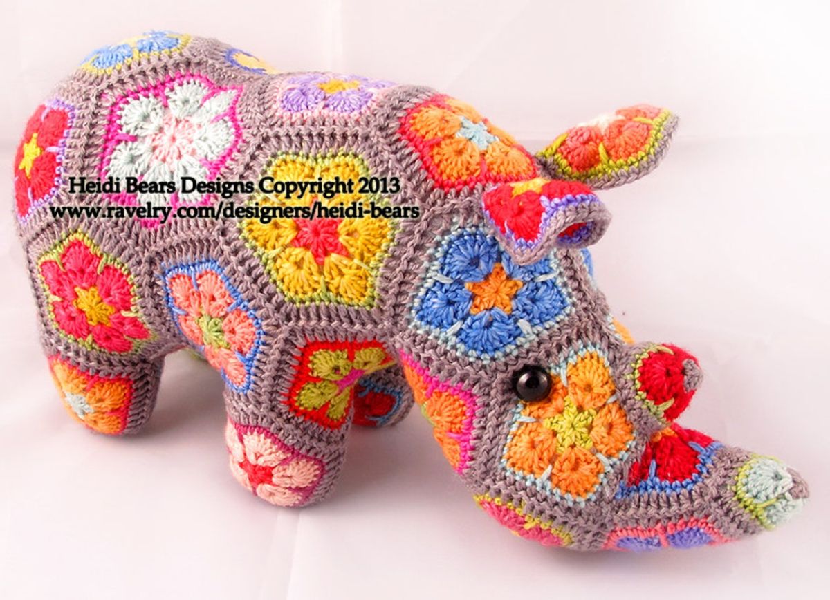 Crochet stuffed Rhino with hexagons of blue, orange, red, brown, green, and pink African flowers and small red horns on its face.