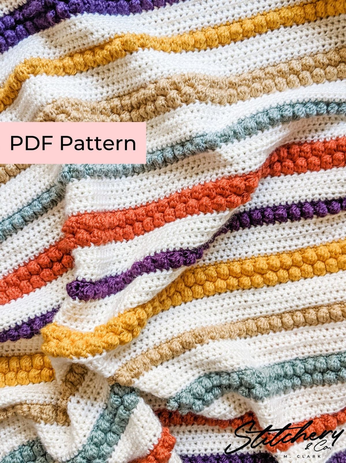 A cream crochet blanket with orange, purple, yellow, and green horizontal stripes using small bobbles all over the blanket.