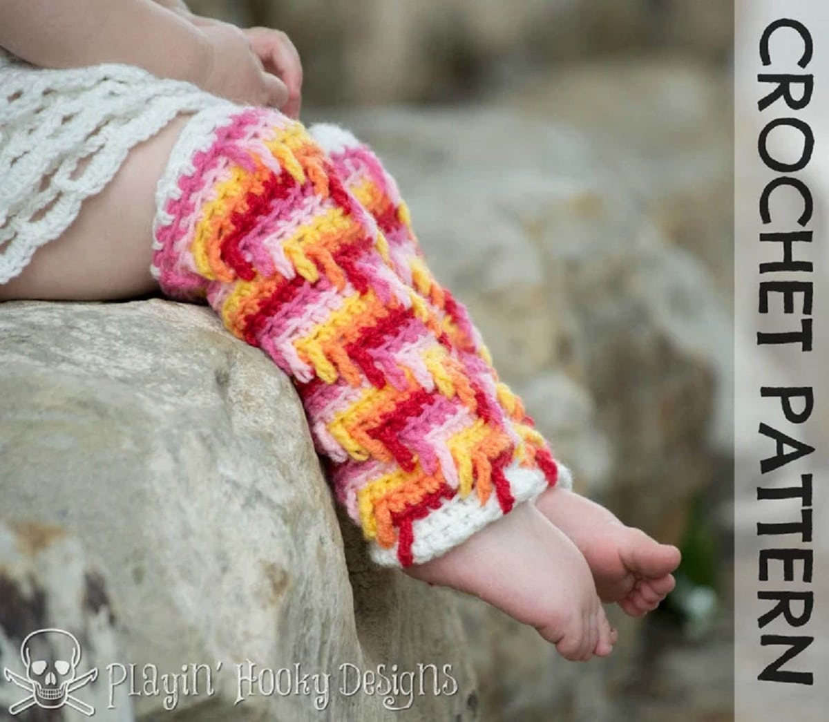 A toddler wearing a trail of tears pattern crochet leg warmers with a pink, red, yellow, orange, and white zig-zag pattern and a white hem.
